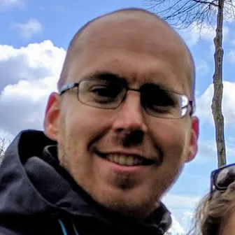 Jan Repnak, smiling, outdoors with a sky background.